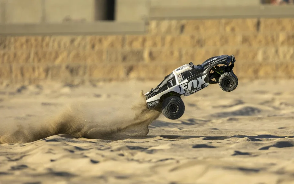 RC short-course truck jumping over sand